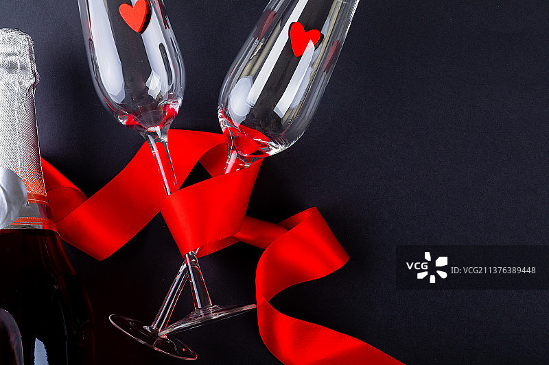 红丝带包装长笛与心形香槟瓶和复制空间在黑色背景图片素材