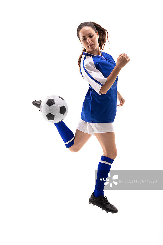 在踢足球时，白人年轻女球员用后脚跟踢足球的全长图片素材