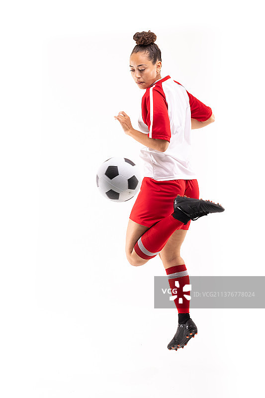 全长双种族年轻女球员踢足球与后脚跟踢足球，而踢足球图片素材