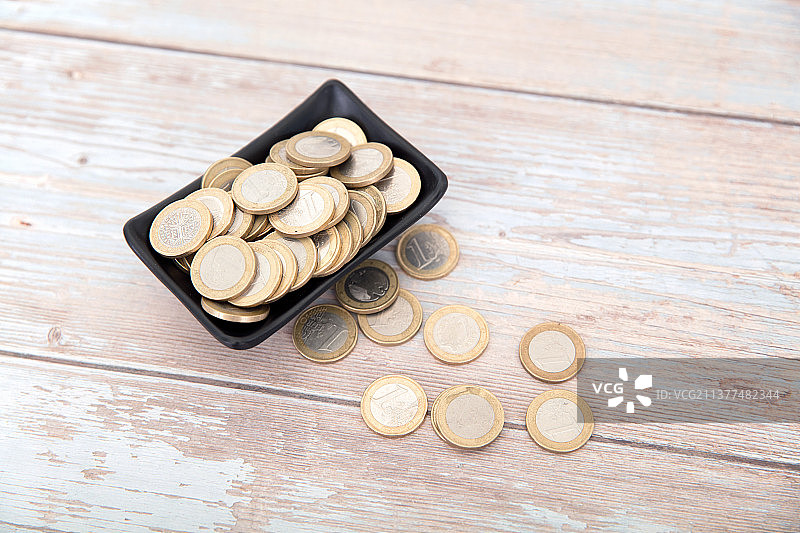桌子上盛满欧元硬币的小碟子和散落的硬币图片素材
