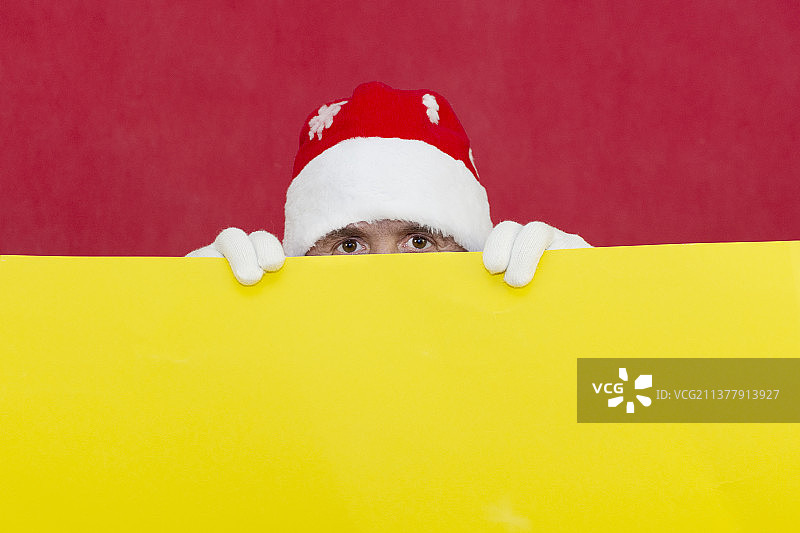 圣诞老人从黄色的背景后面探出头来图片素材