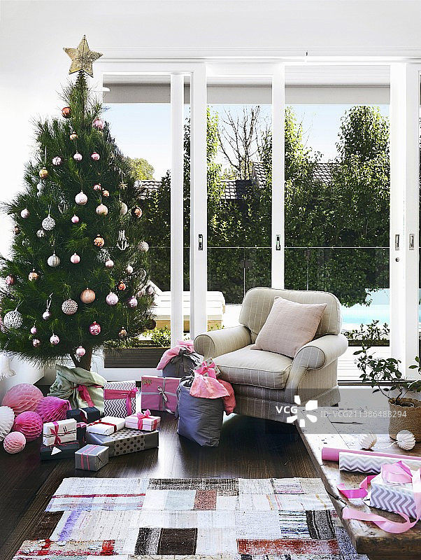 澳大利亚客厅装饰圣诞树，包装礼物和舒适的软垫扶手椅图片素材