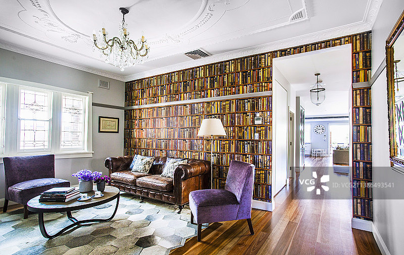 皮革沙发和落地灯在图书馆的复古墙纸前，紫色软垫椅子和茶几在客厅图片素材