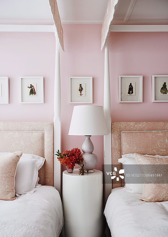 粉红色卧室里两张柱子床之间的圆桌图片素材