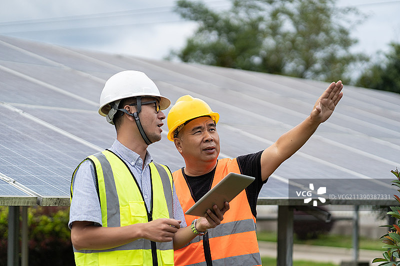 太阳能光伏板前交流的两名男性工程技术人员图片素材