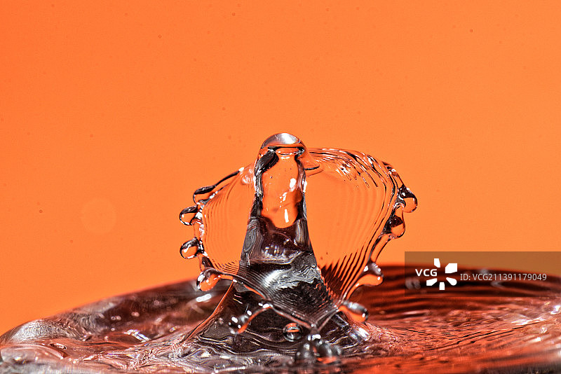 橙色背景下飞溅的水滴特写图片素材