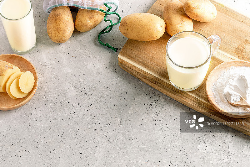 玻璃中的土豆粉制成的土豆牛奶，土豆粉，混凝土上的木制厨房板上的块茎，俄罗斯图片素材