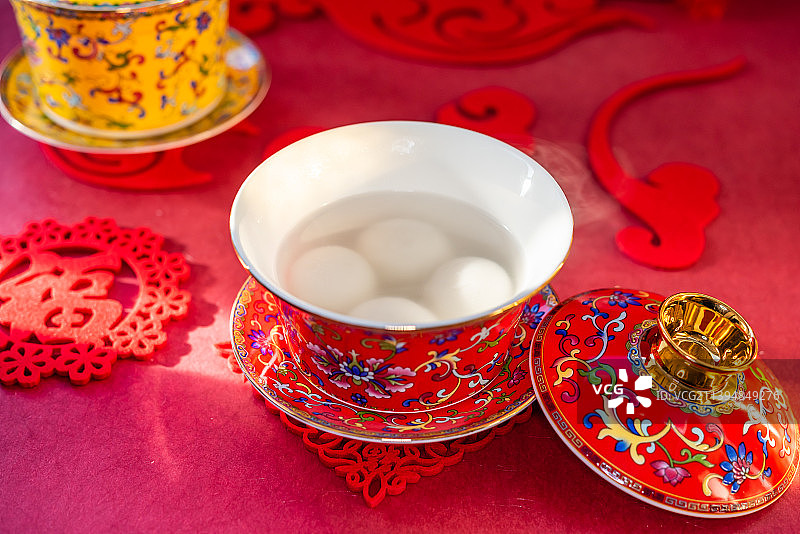室内棚拍红色中国风背景前的一碗煮熟的元宵图片素材