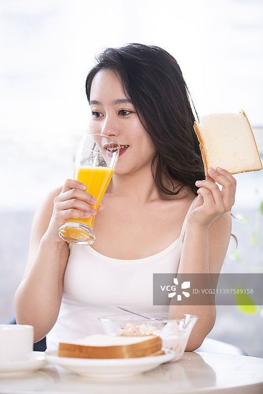 漂亮的年轻女子在家吃早餐图片素材