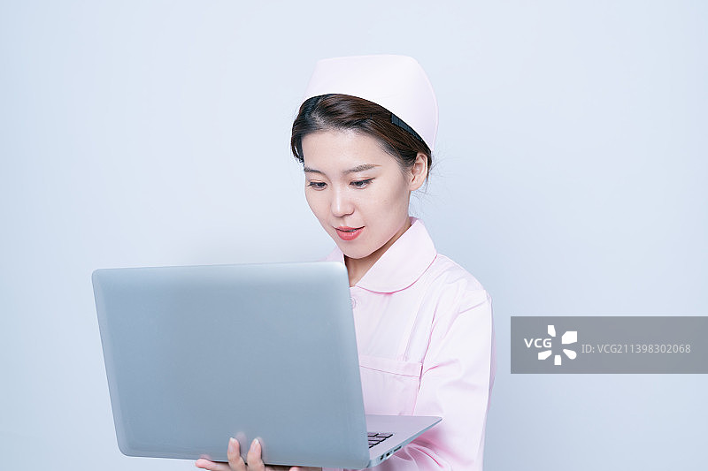 白背景里穿护士服使用笔记本电脑的女护士图片素材
