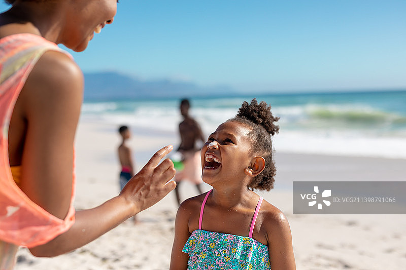 欢快的非洲裔美国母亲和女儿在海滩上与家人享受阳光，拷贝空间图片素材