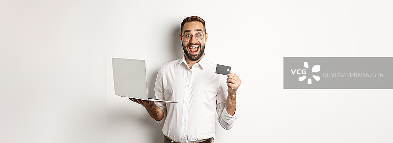 网上购物帅哥出示信用卡，用笔记本电脑图片素材