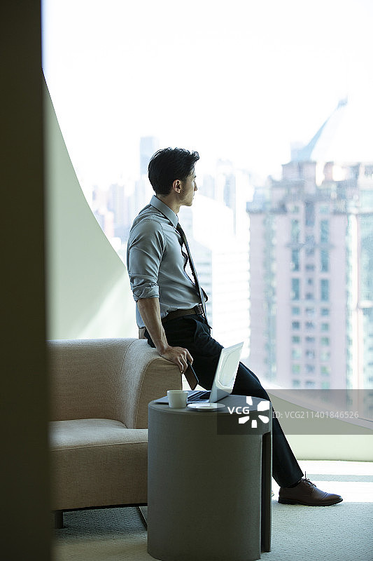 商务男子在酒店房间工作后看窗外风景放松图片素材
