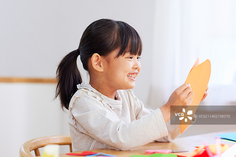 一个日本小孩在家里玩折纸图片素材