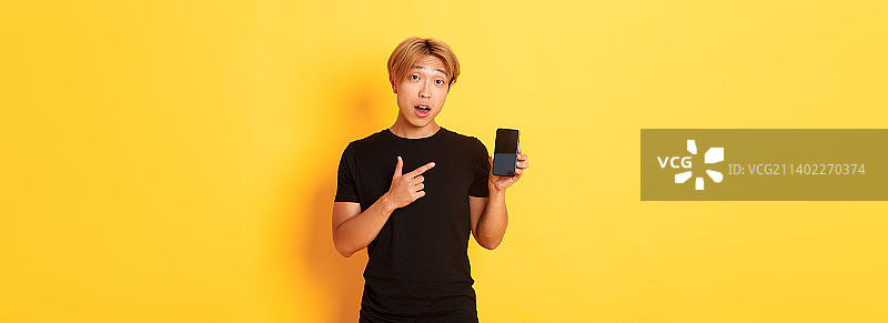 英俊的亚洲男子的肖像在智能手机屏幕上显示一些东西图片素材