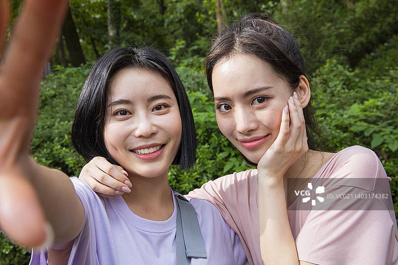 两名20多岁的韩国亚裔女性朋友在山上徒步旅行并自拍图片素材