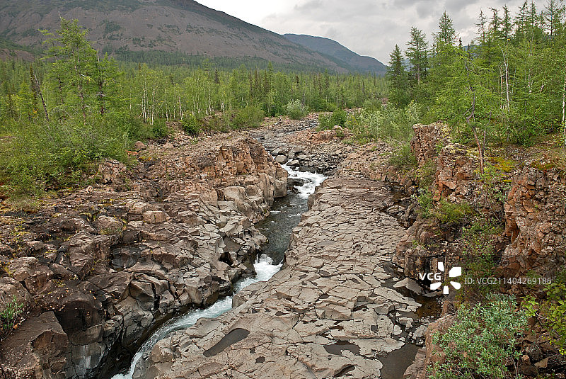俄罗斯Putorana高原，小溪穿过岩石，迎着天空的风景图片素材