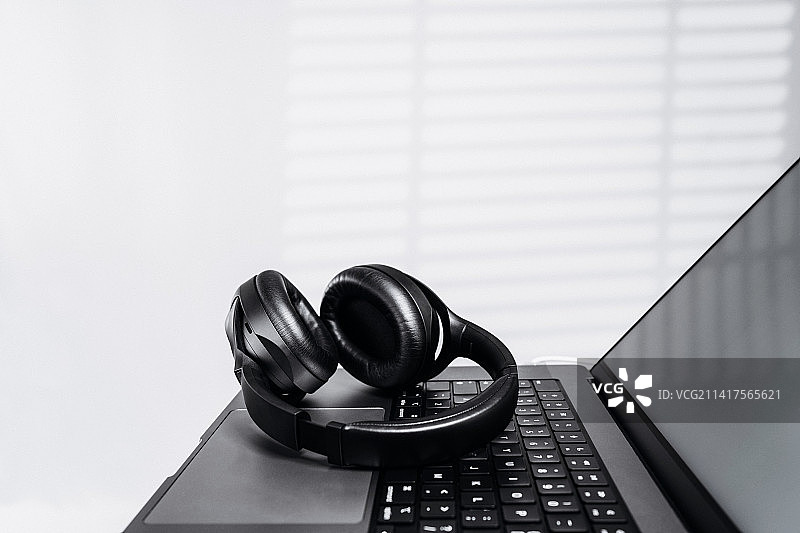 休息时，笔记本电脑上戴着现代无线耳机图片素材