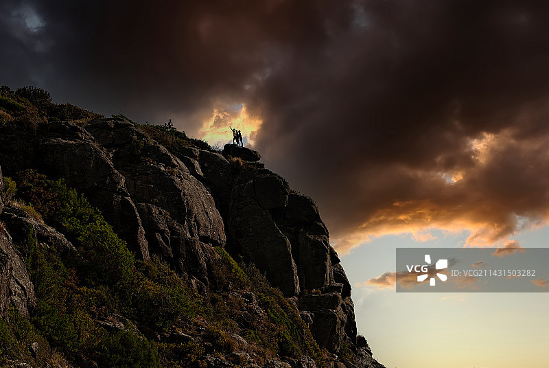 日落时岩石上的人的低角度视图图片素材