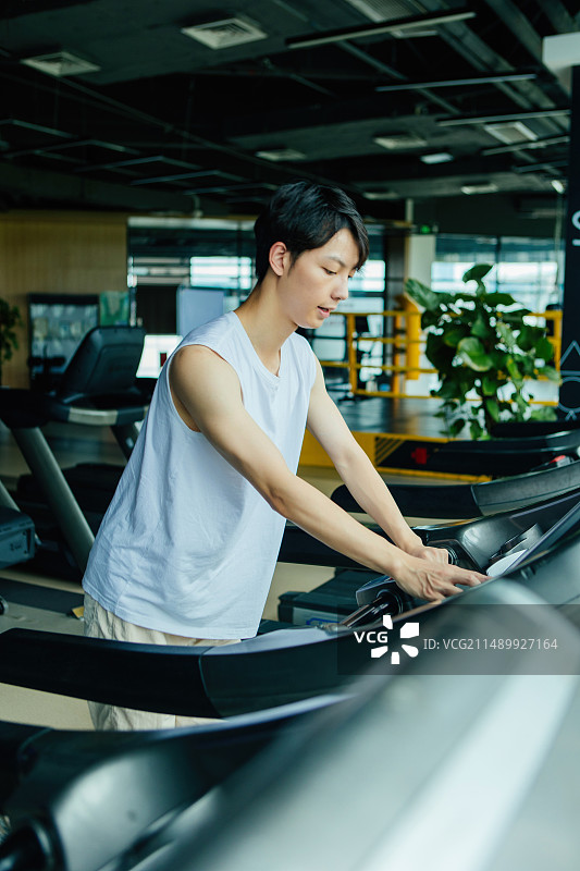 一个亚洲男性在跑步机上进行跑步健身运动图片素材