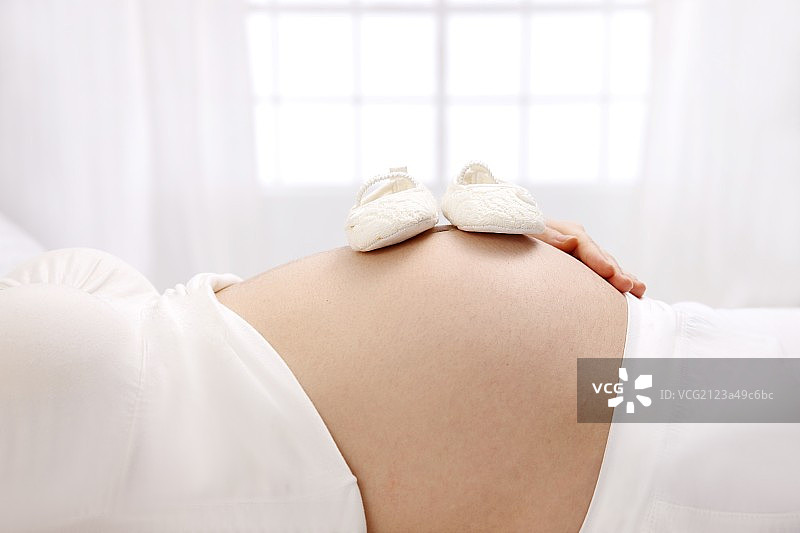 婴儿鞋子放在孕妇的肚子上图片素材