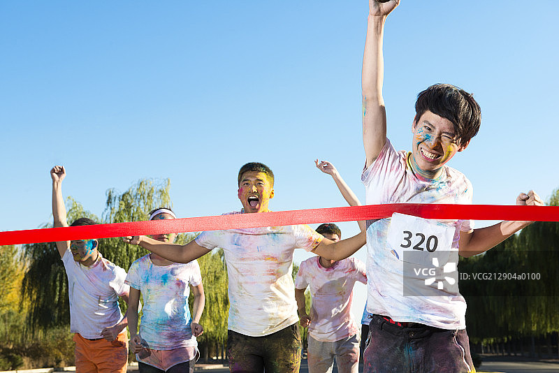 Young man crossing finishing line at The Color Run图片素材