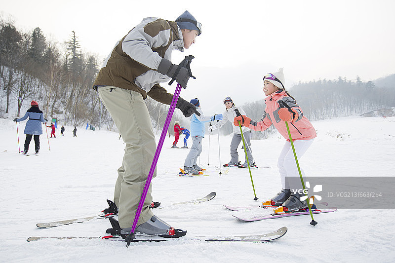 年轻的父母教子女滑雪图片素材
