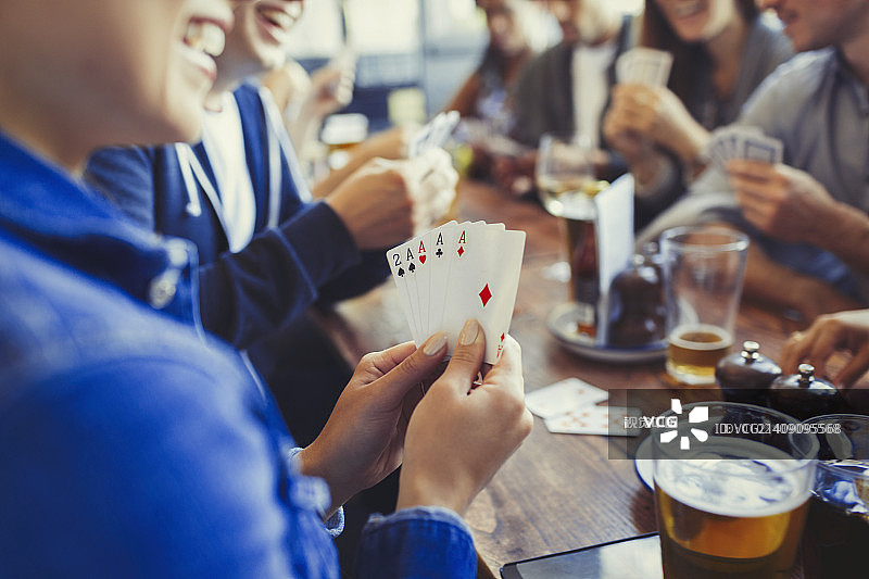 拿着a的女人，打扑克，和朋友在酒吧的桌子上喝啤酒图片素材