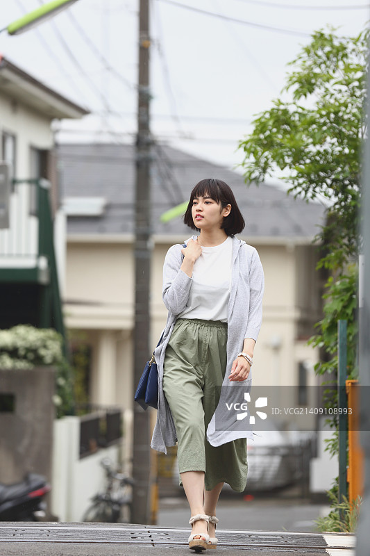 一个年轻的日本女人站在外面的铁轨旁图片素材