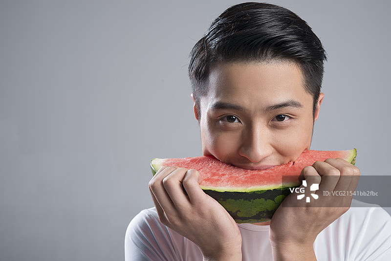 Young man eating watermelon图片素材