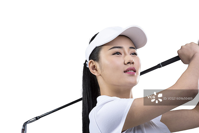 Young female golfer swinging golf club图片素材