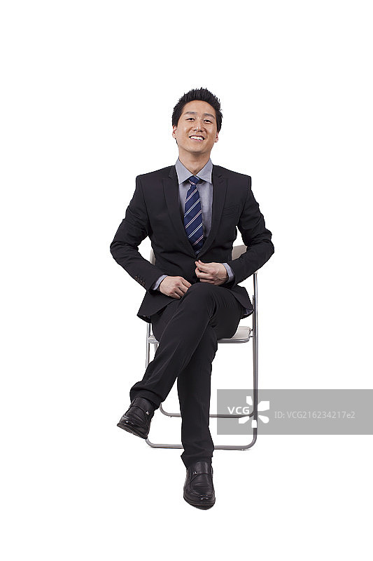 一个坐在白色折叠椅上的青年商务男士图片素材