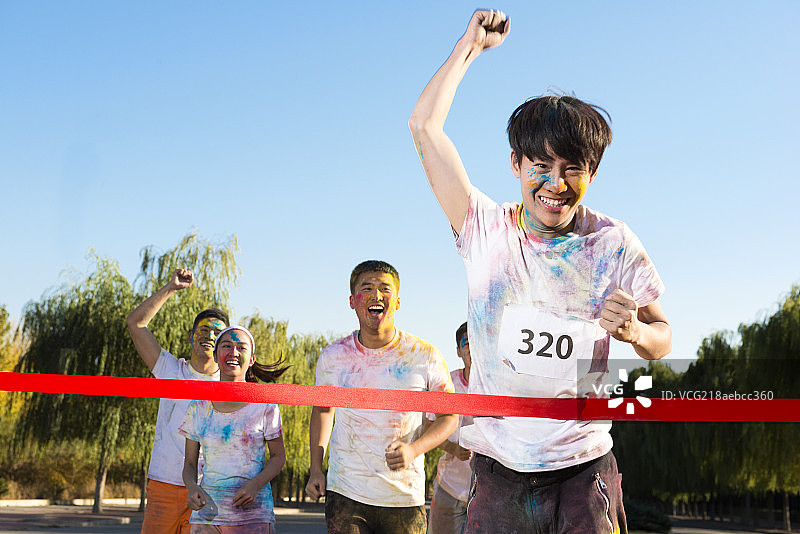 Young man crossing finishing line at The Color Run图片素材