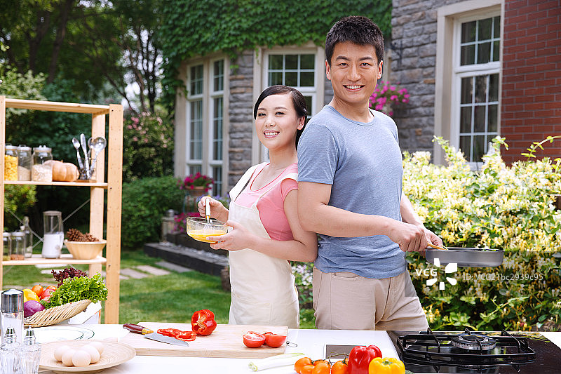 年轻夫妇在户外厨房做饭图片素材