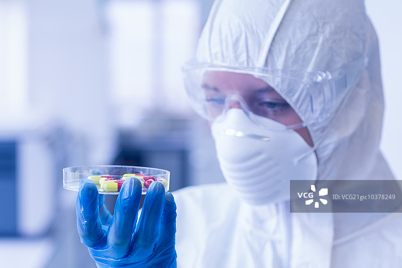 一个科学家在防护服分析药片在实验室的特写图片素材