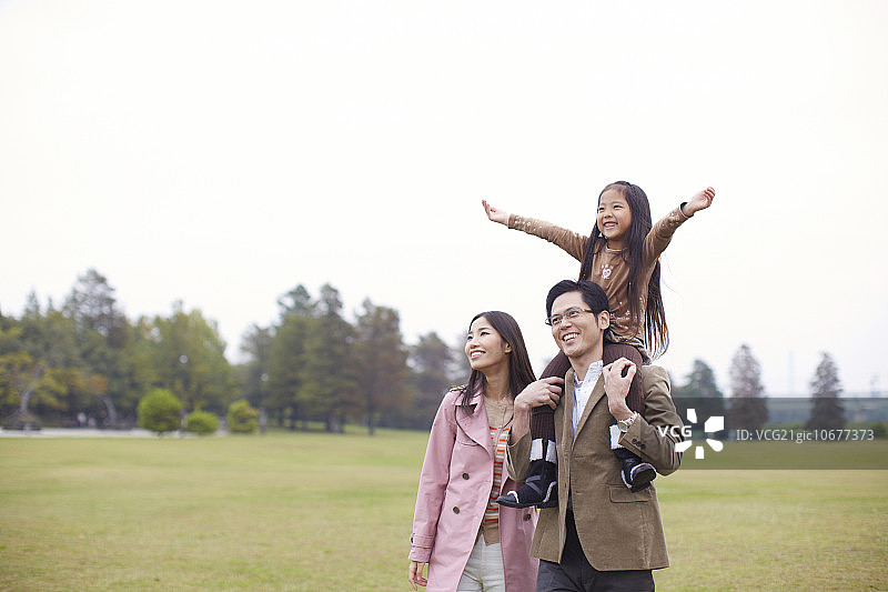 三口之家在公园，女儿在父亲的肩膀上图片素材
