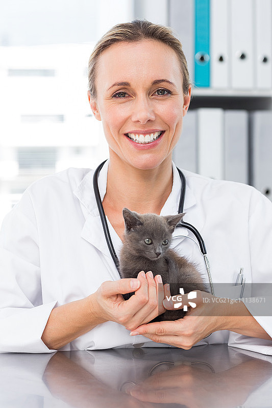 肖像快乐的女兽医抱着小猫在诊所图片素材