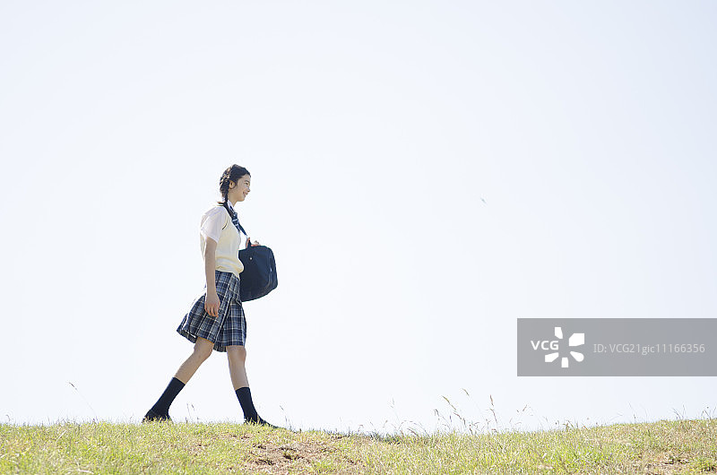 穿着校服的少女，走在田野里图片素材