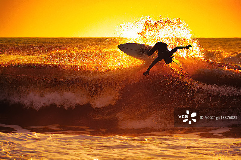 一个人在日落时冲浪。图片素材