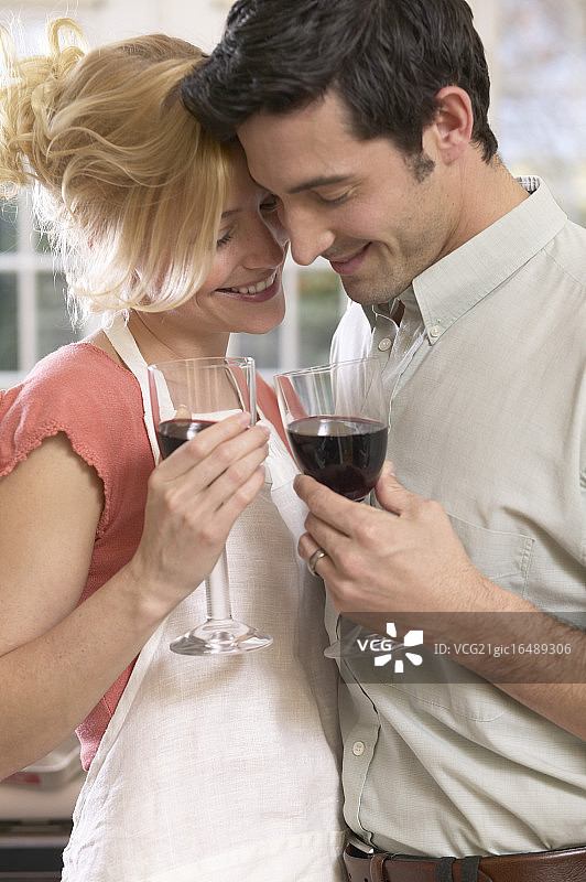 厨房里一对深情的情侣端着红酒图片素材