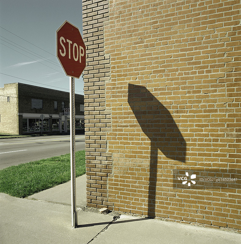 一个“停止”的路标在砖墙上投下了阴影图片素材