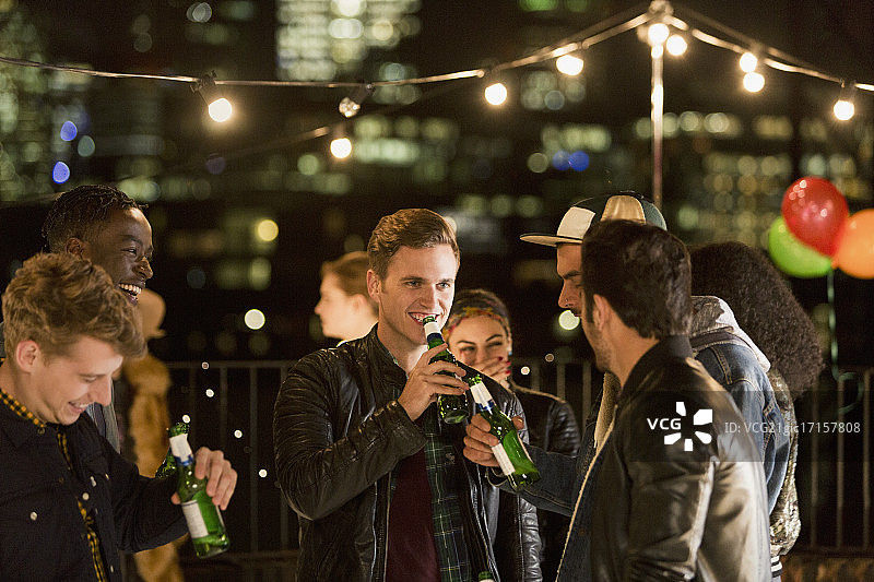年轻人在屋顶派对上喝啤酒图片素材