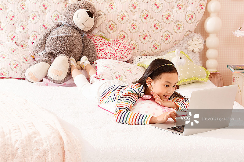 小女孩在床上使用笔记本电脑图片素材