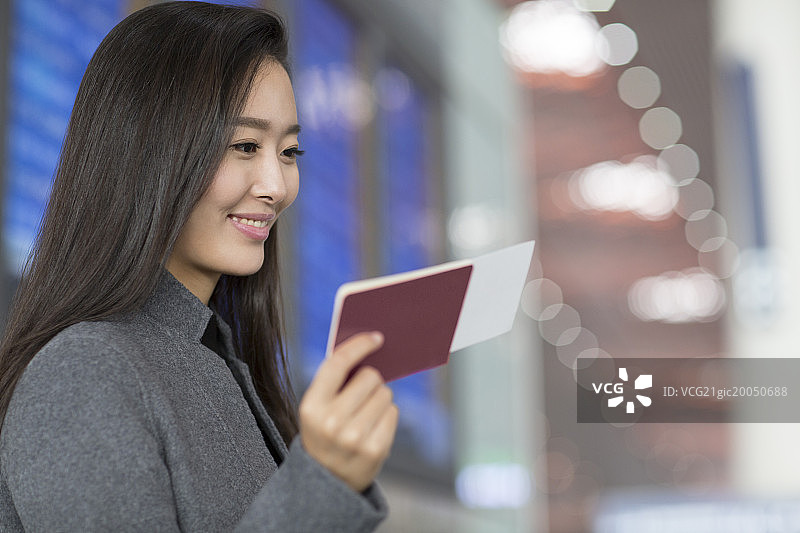 年轻商务女子拿着机票和护照在机场等候图片素材