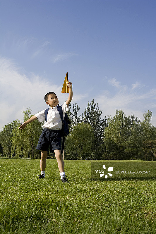 在草地上玩纸飞机的小男孩图片素材