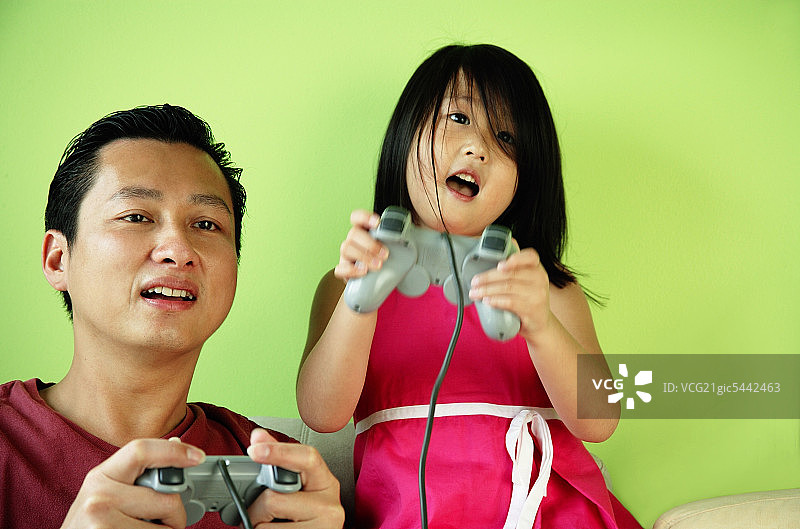 父亲和女儿，肩并肩，玩电子游戏图片素材