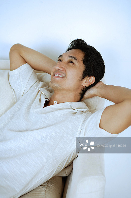 男人躺在沙发上，手放在脑后，微笑着图片素材