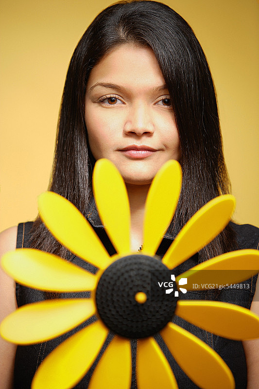 年轻的女子在黄色的背景下，针轮在她的前面图片素材