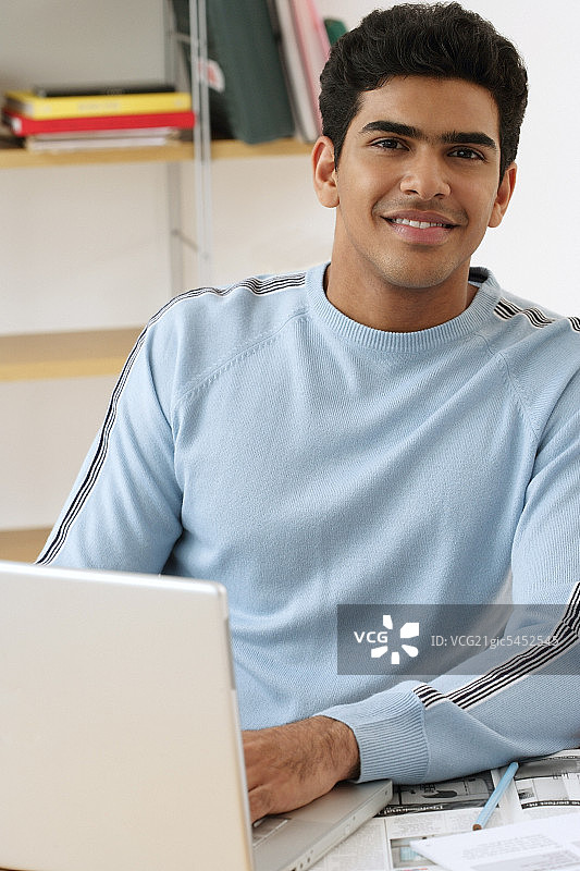 年轻人拿着笔记本电脑对着镜头微笑图片素材