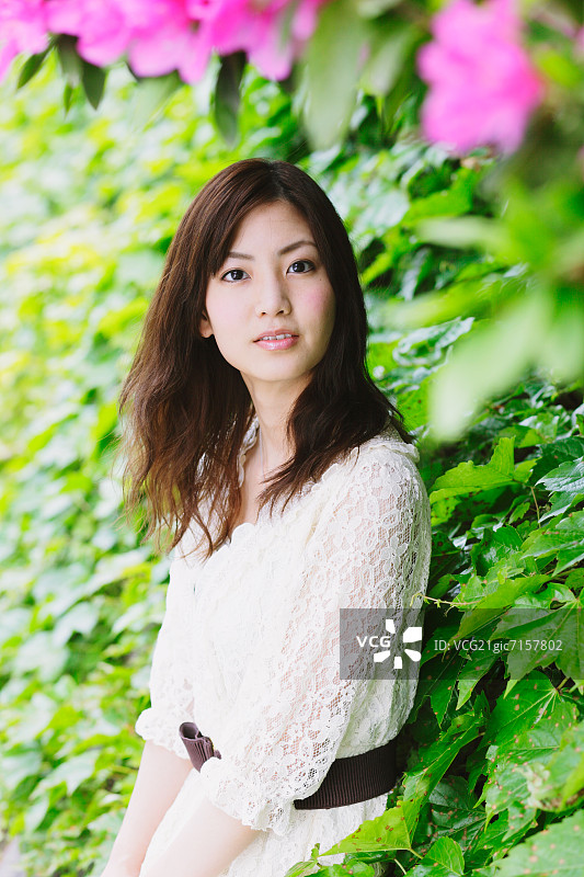 一个日本女人被绿叶包围着看着相机图片素材